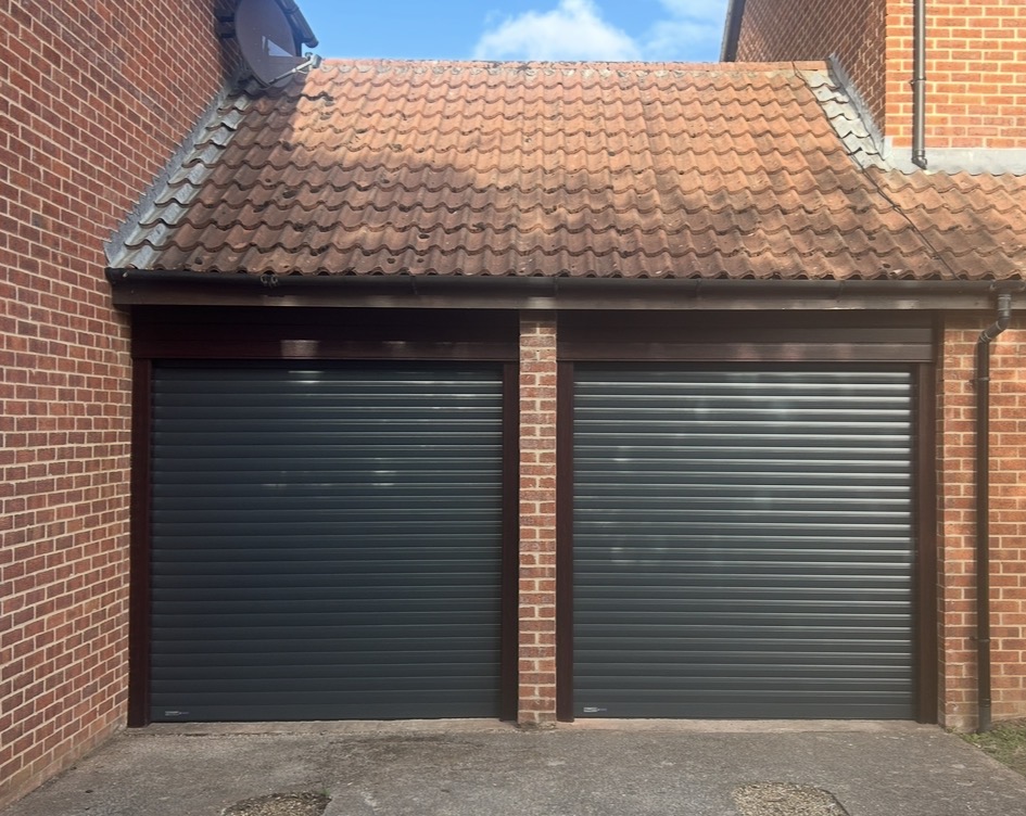 Pair of anthracite roller garage doors under a tiled roof