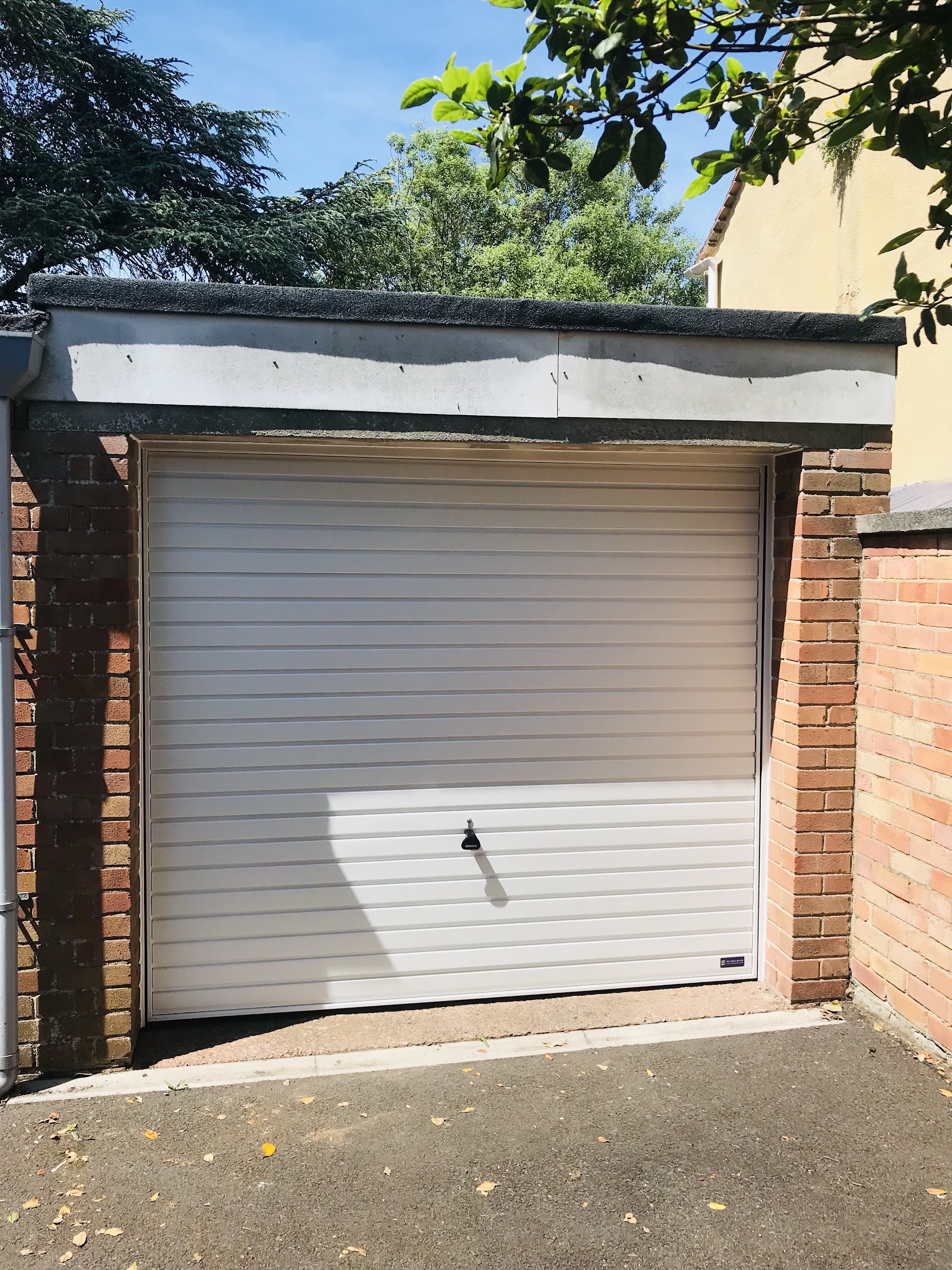 White garage door fitted to a single garage with a flat roof