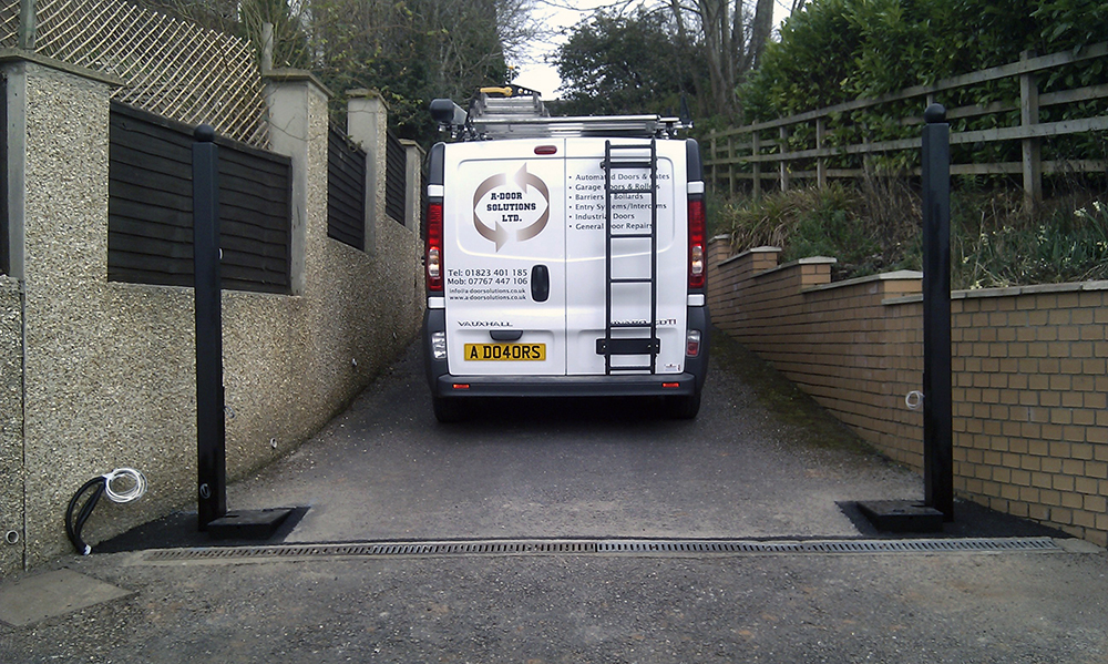 New gate posts installed on a long driveway with the A-Door Solutions van between them
