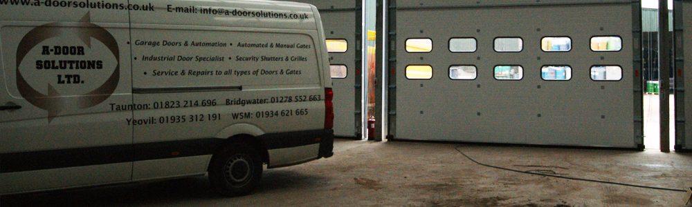 A-Door Solutions vans parked in front of green sectional industrial doors